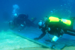 Divers laying out the clam control mats. Mats are designed to decrease oxygen levels beneath the barrier to suffocate and kill off clam populations. . 